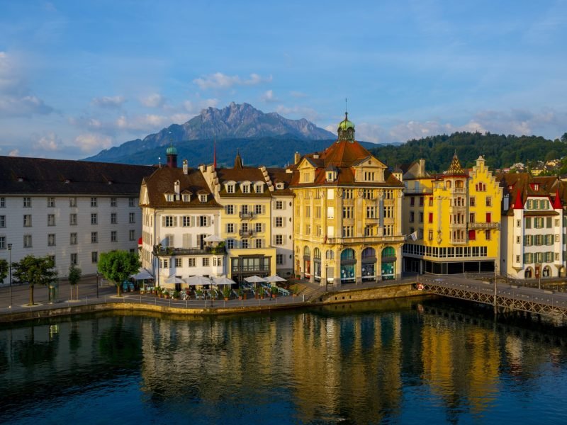 The colorful buildings near a river surrounded by mountains in Lucerne in Switzerland
